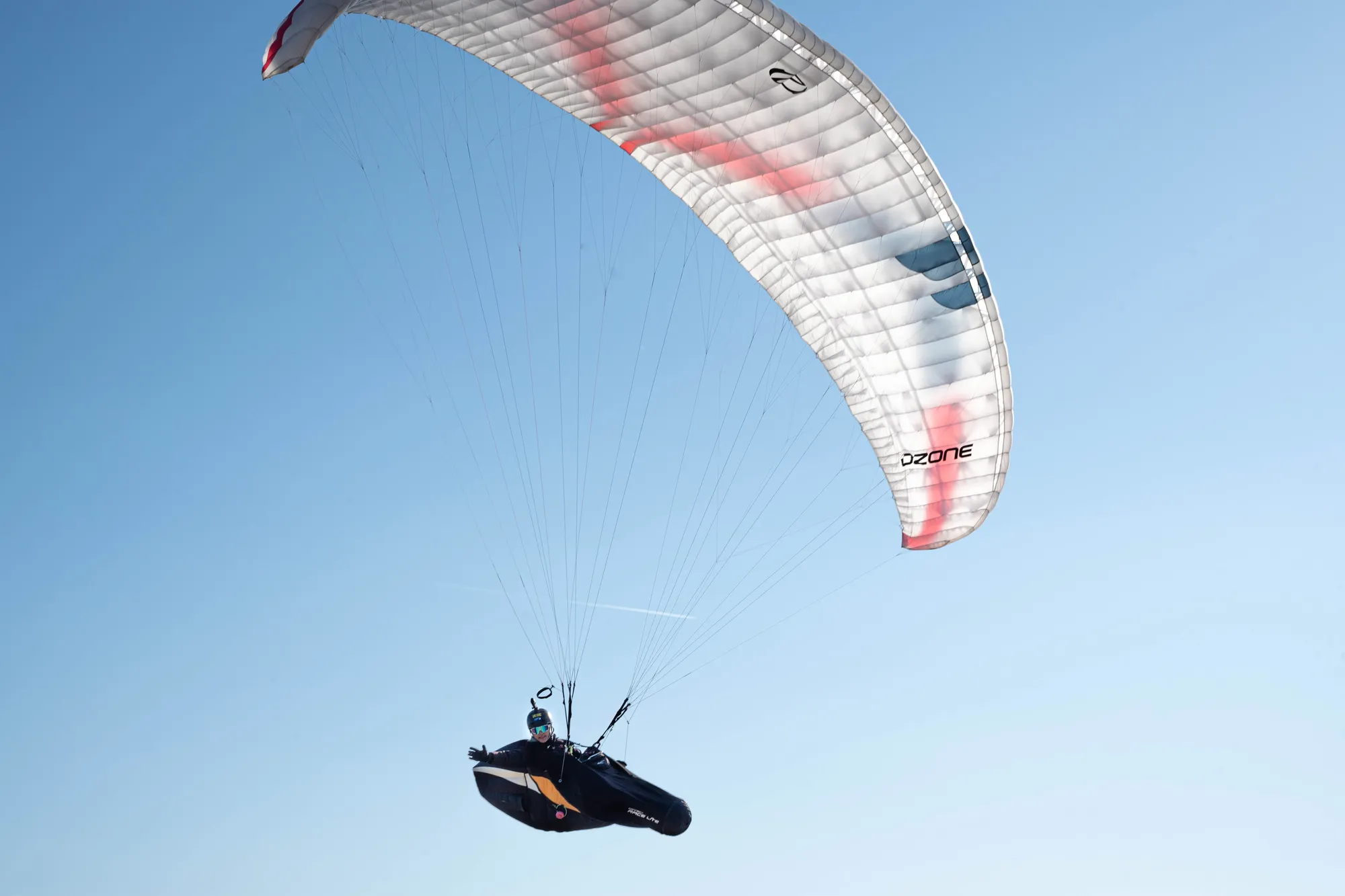 Parapendio ripreso da vicino, la vela bianca e rossa spiegata e il pilota nell'imbrago